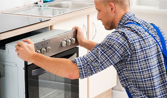 Technician kneeling down installing a oven using the MobiWork Home Repair & Installation services software solution